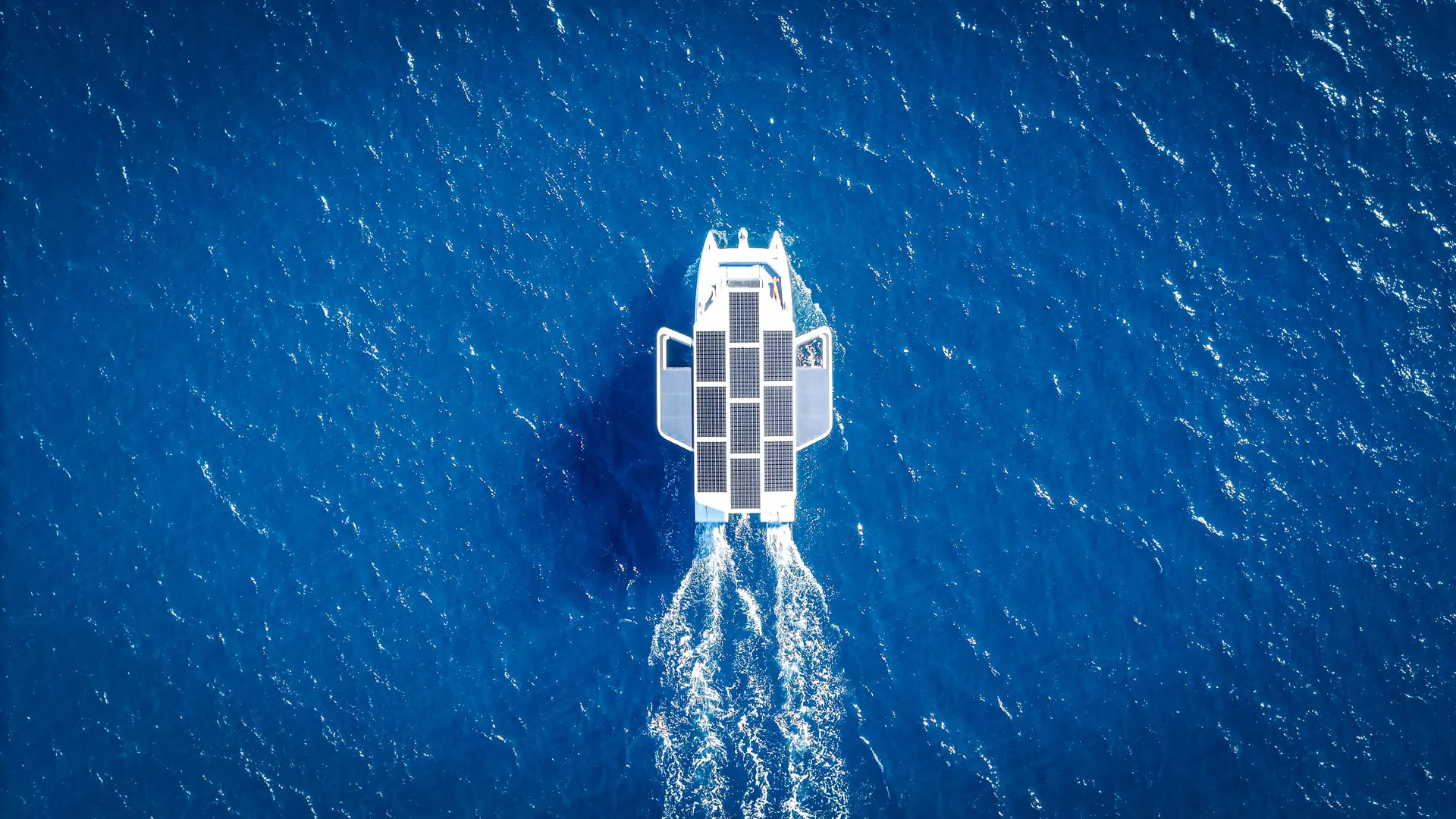 The M10 seen from directly above, solar roof and wake on deep blue water